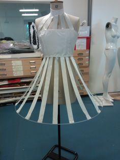 a mannequin wearing a dress made out of strips of white paper and ribbon