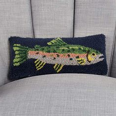 the back of a chair with a fish pillow on it's arm and side