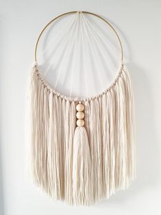 a white wall hanging with wooden beads and tassels on the end of it