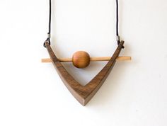 a wooden object hanging from a string on a white wall with a ball in the middle