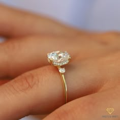 a woman's hand holding a ring with a diamond on the top and side