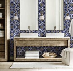 a bathroom with blue and white tiles on the wall, two sinks and mirrors above them