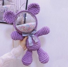 a person holding a purple teddy bear in front of a mirror with beads on it