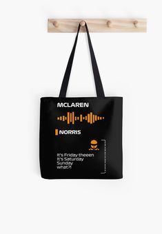 a black tote bag hanging from a wooden hanger with an orange and yellow design