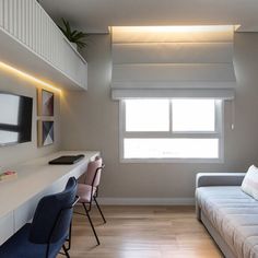 a living room with a couch, desk and television on the wall next to it