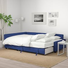 a bed with white sheets and pillows on top of it next to a blue couch