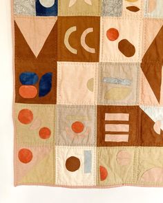 a quilted wall hanging with various shapes and sizes on it's side,