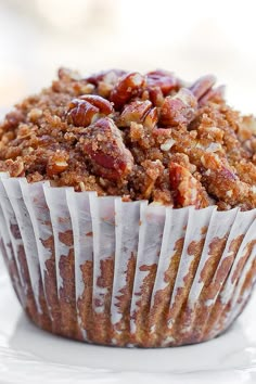 a muffin is sitting on a plate with white frosting and pecans in it