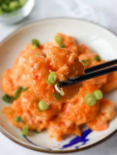 a spoon full of food on top of a plate with chopsticks in it