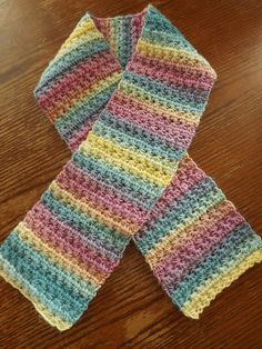 two crocheted scarfs sitting on top of a wooden table