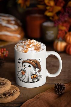 a cup of hot chocolate with marshmallows on top and pumpkin decorations in the background