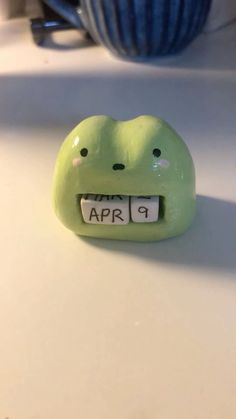 a green frog shaped alarm clock sitting on top of a counter