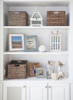 a white bookcase with baskets and pictures on it