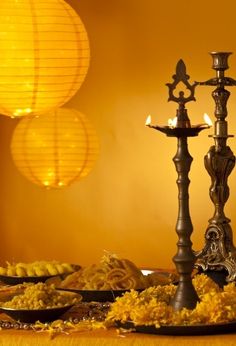 a table topped with lots of food and two lit candles on top of plates next to each other