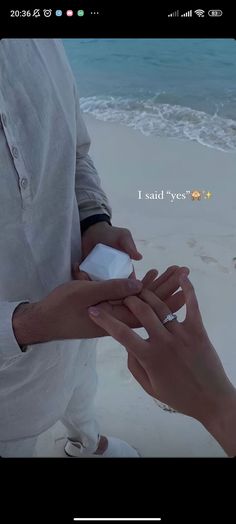 two people standing on top of a beach next to the ocean holding each other's hands