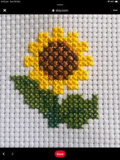 a cross stitch sunflower with green leaves on the bottom and yellow petals on the top