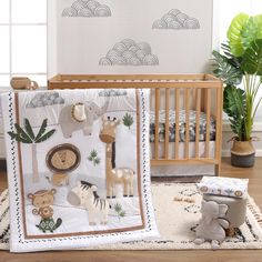 a baby crib bedding set with animals and plants on the wall next to it