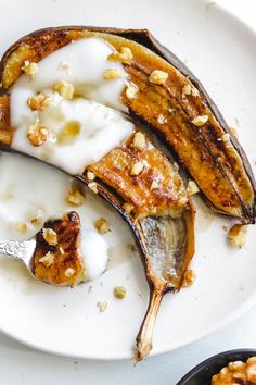 a white plate topped with banana slices covered in yogurt and walnuts next to a bowl of granola