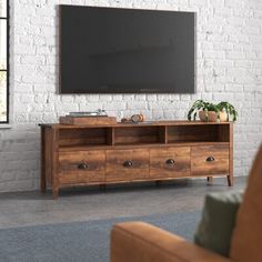 a living room with a couch, television and brick wall in the backround