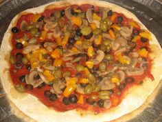 an uncooked pizza with olives, peppers, and mushrooms on a metal tray