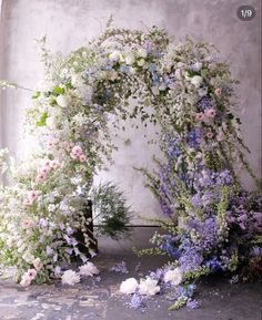 an arch covered in flowers and greenery next to a wall