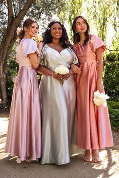 three women standing next to each other in dresses