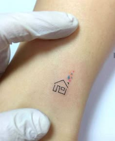 a small house tattoo on the right side of the left arm, with stars coming out of it