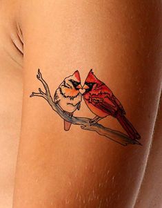 a woman's thigh with a bird tattoo on the back of her leg, and a red cardinal sitting on top of it