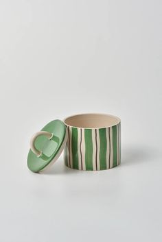 a green and white striped container sitting on top of a table next to a cup