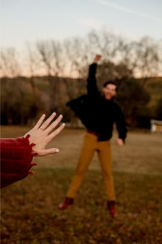 two people are playing with a frisbee in the park while one person holds out their hand