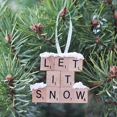 a wooden block ornament that says let it snow hanging from a pine tree