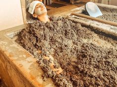 a man with a towel on his head sitting in a bathtub filled with dirt