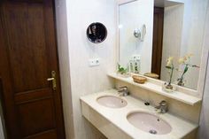 a bathroom with two sinks and a mirror on the wall next to a door that leads to another room