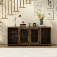 a wooden cabinet sitting in front of a stair case with pictures on the wall behind it