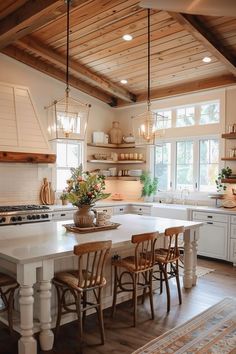 a large kitchen with white cabinets and wooden beams on the ceiling, along with an island table surrounded by four chairs