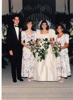 a group of people standing next to each other in front of a wall with flowers