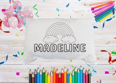 a pillow with the word madeline on it surrounded by colored pencils and confetti