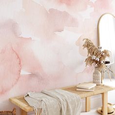 a pink and white watercolor wallpaper with a wooden bench in front of it