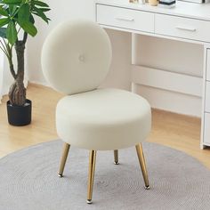 a white chair sitting on top of a rug in front of a desk with a potted plant