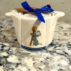 a ceramic cup with a blue bow on the top and an image of a mouse holding a baseball bat