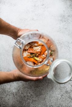 a person holding a glass pitcher filled with food