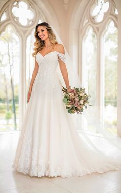 a woman in a wedding dress is posing for the camera with her veil over her shoulder