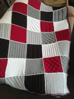 a crocheted blanket sitting on top of a couch next to a pillow in the shape of a square