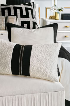 black and white pillows sitting on top of a bed