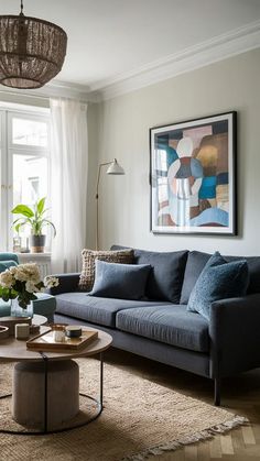 a living room filled with furniture and a painting hanging on the wall above it's windows