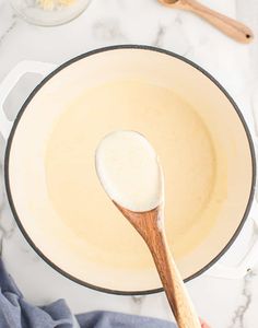 a person holding a wooden spoon over a pot filled with batter and other ingredients on the counter