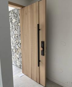 a wooden door is open in front of a wall with rocks on it and a phone