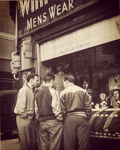 an old photo of men standing in front of a store