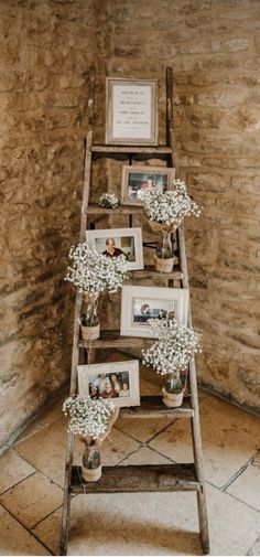 an old ladder with pictures and flowers on it in the corner of a stone walled room