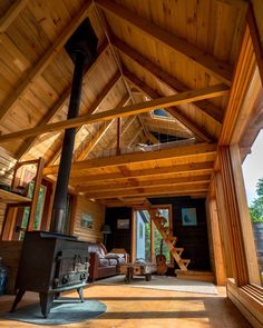 the inside of a log cabin with wood flooring and exposed ceilings, including an open fire place